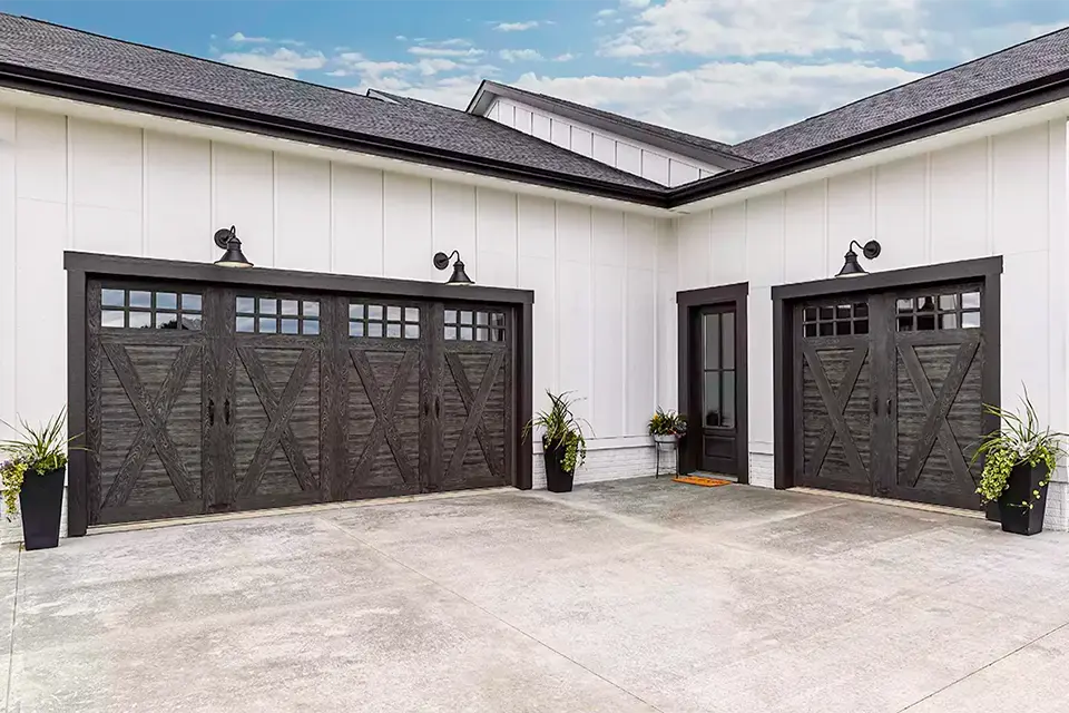 Carriage house style garage door with a swing-out appearance and iron hardware.